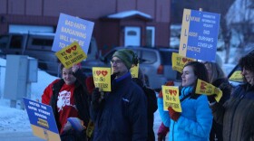 people in winter jackets wave signs