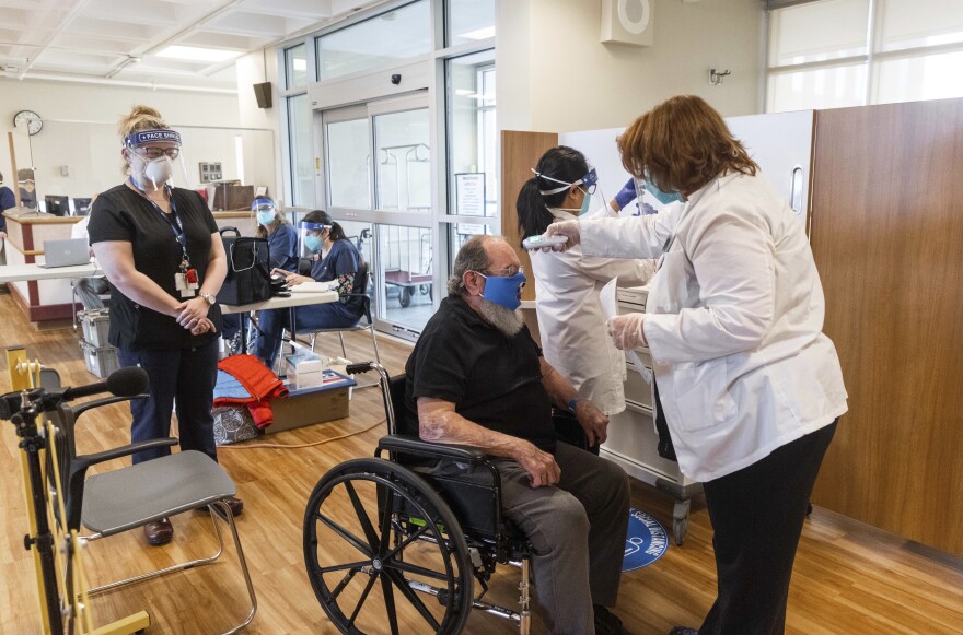 U.S. Air Force Veteran Robert Aucoin, 78, gets his temperature checked prior to receiving his COVID-19 vaccine at the Soldiers' Home in Holyoke, Mass., on Dec. 29, 2020. 