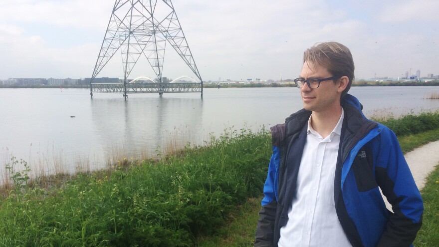 Dennis van Berkel, an attorney with Urgenda, stands on the outskirts of the city on an earthen berm. The level of the water is higher than the land on the other side of the berm.