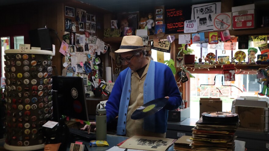 House of Records owner Greg Sutherlin cleans records behind the counter on April 7, 2026. He began working at the shop 40 years ago.