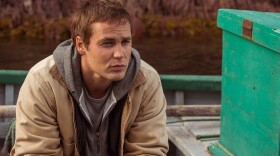 Taylor Kitsch plays Paul Lewis, a doctor in demand, in <em>The Grand Seduction</em>. It's a classic tale of an outsider discovering the appeal of a small town — except the rustic charm is manufactured for Lewis' benefit.