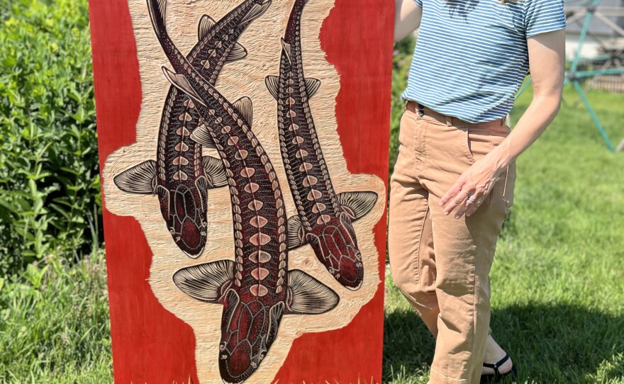 Jabs holds her woodcut block of Lake Sturgeon, which was carved for the 2025 Really Big Prints steamroller printing event.