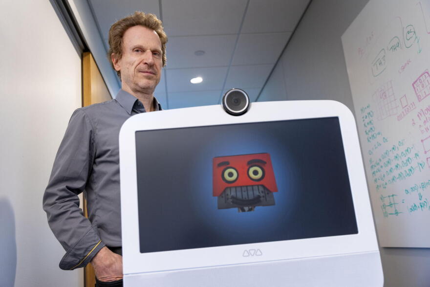 Professor Matthias Scheutz follows AVA along a hallway at the Human Robot Interaction Lab, at Tufts University.