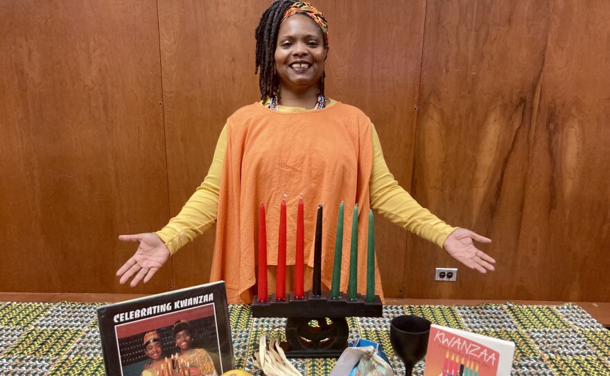 Shukrani Gray, African American Resource Collection, Equity and Inclusion Librarian at New Orleans Public Library, with a Kwanzaa kinara and other holiday materials.