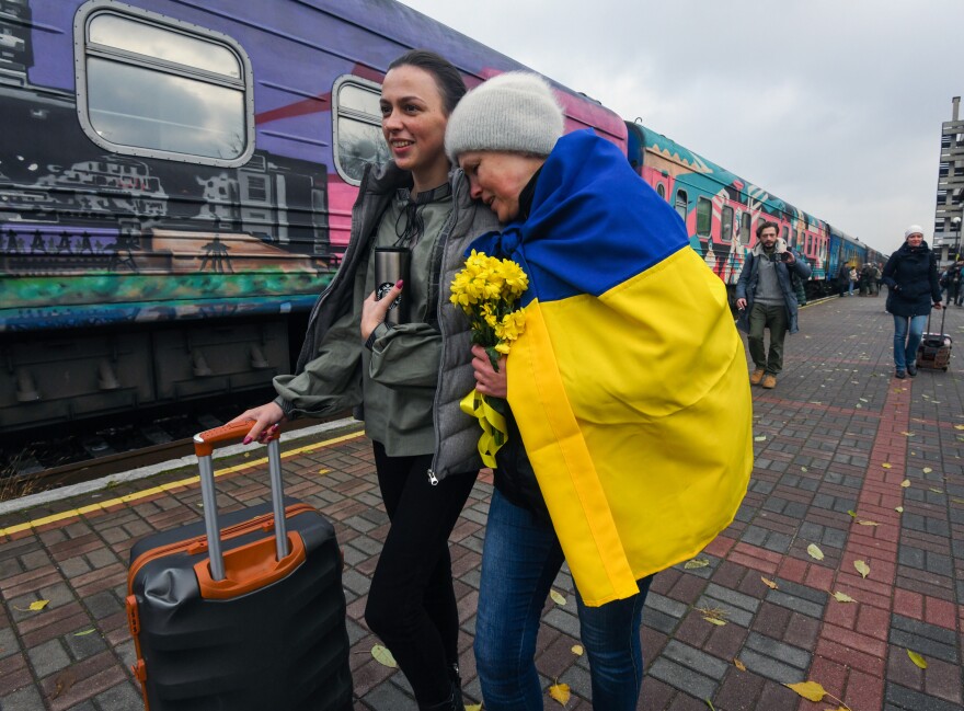 Oksana Shevliuha, 51, wears a Ukrainian flag as she greets her daughter, Anastasia, who arrived on the first train to reach liberated Kherson on Saturday. They had not seen each other for six months. The first Ukrainian Railways train arrived in Kherson following a Russian occupation that lasted more than eight months.