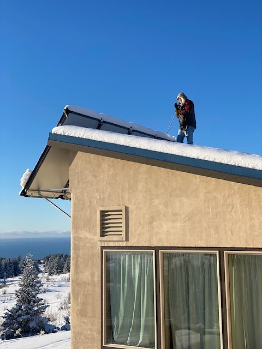 Scott Waterman clears snow off his solar panels in Homer. Solar panels are among the technologies incentivized in the Inflation Reduction Act.