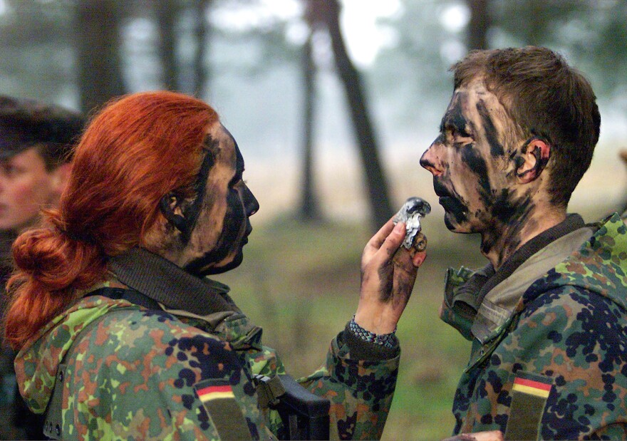 Private Dajana Bartczewski (left) puts camouflage paint on the face of a male soldier during an exercise by German Bundeswehr soldiers from the barracks in Augustdorf, western Germany, on Jan. 9, 2001.