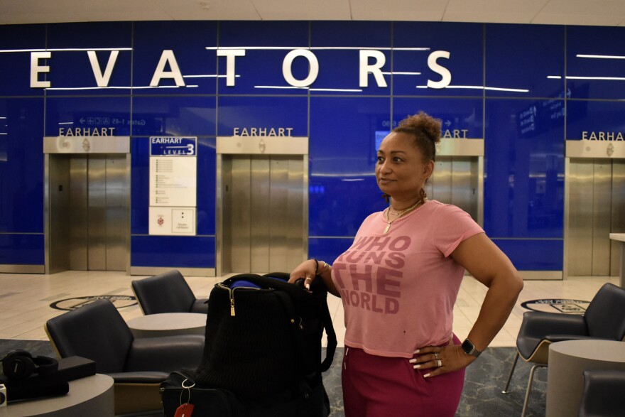 A woman in a pink outfit stands next to her luggage in the main terminal of Tampa International Airport