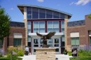 An eagle statue rises before the front doors of a modern building.