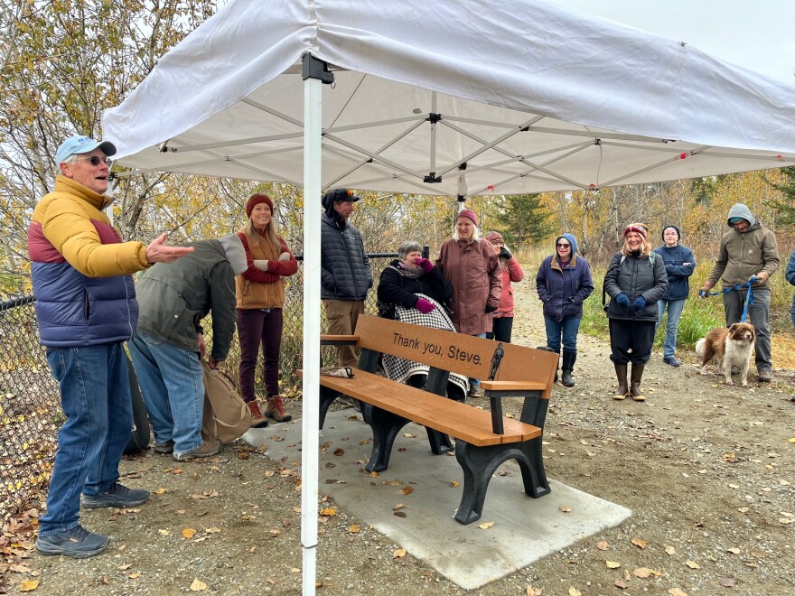 John Sloan greets friends of Steve while he and Bill Johnson, second from left, prepare to play a couple of songs for during the ceremony at Delta River Walk Park
