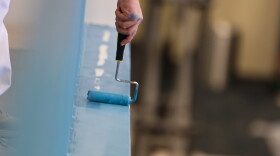 One of the volunteer paintings touches up the railing of the Gateway's lobby