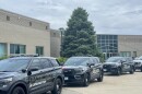 A row of black police cars and parked at the curb next to a building