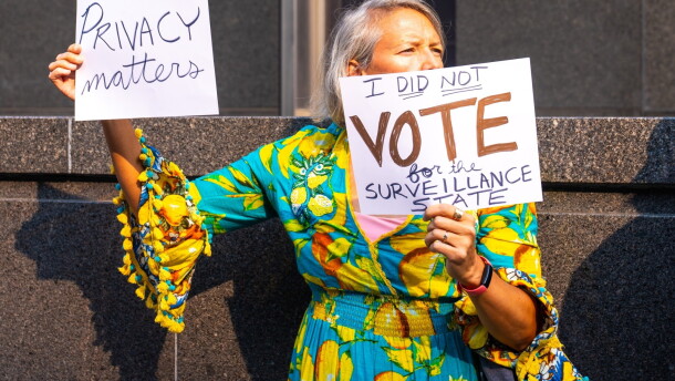 A protester holds up anti-Flock placades outside Richmond City Hall during a demonstration against Flock cameras before a City Council meeting on July 27, 2026.