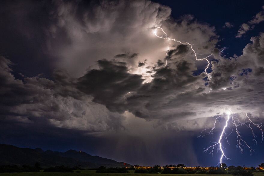 Lightning strikes the ground across a dark blue stormy sky