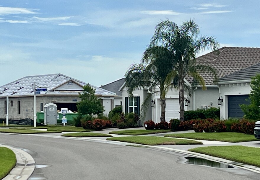 A view of three houses on a road. One house is getting a new roof. 