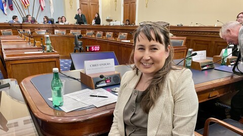 Woman in a hearing room, turning toward camera