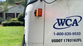 A WCA truck stops in front of a Gainesville house for curbside pickup. The truck, one of 55 that services Alachua County, collected waste and recycling from the respective bins before continuing on its route. WCA is one of the area's privately-contracted trash and recycling collection firms. (Natalia Galicza/WUFT News)