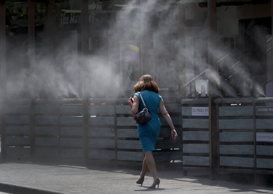 A woman walks along a row of misters on June 19, 2017 in Tempe, Ariz., when the temperatures were over 110 degrees.