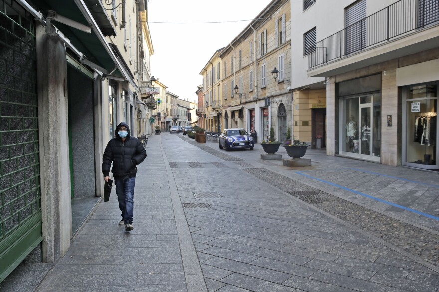 A man wearing a face mask walks along a street in Codogno, in northern Italy.