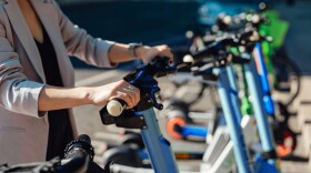 FILE: Close-up of woman hands holding the handlebars of electric scooter.
