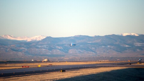 An airplane taking off with the snow-capped Rocky Mountains in the background as viewed from Denver, Colorado.