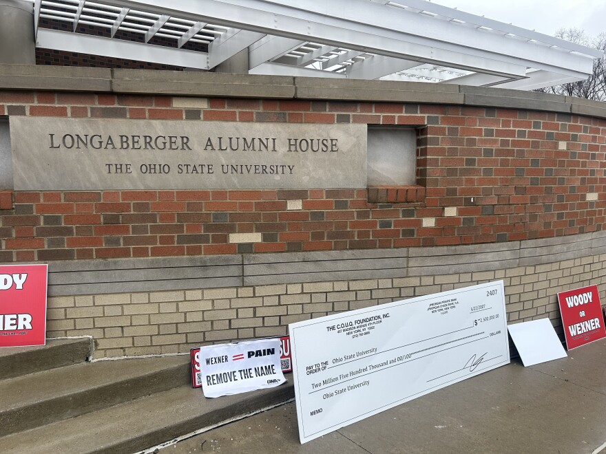 Protesters set signs down outside the Longaberger Alumni House at 2200 Olentangy River Rd., where the OSU Board of Trustees meet, after Thursday's meeting adjourned.