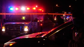 A federal immigration officer lifts police tape to let an ambulance through at the scene of a reported shooting Wednesday, Jan. 14, 2026, in Minneapolis. (AP Photo/John Locher)