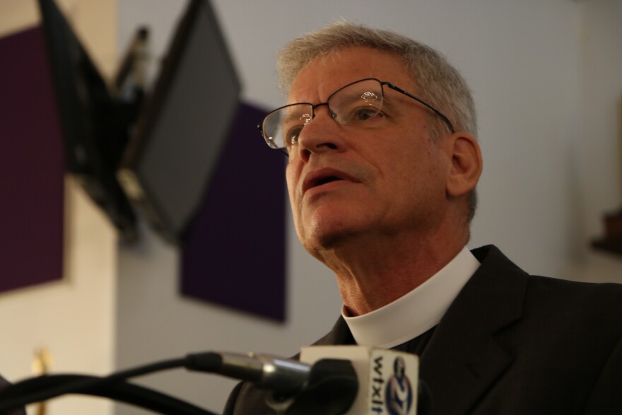 Pastor Brant Copeland looks toward a crowd of reporters.