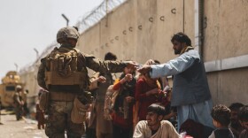 KABUL, AFGHANISTAN - AUGUST 21:  In this handout provided by the U.S. Marine Corps, a Marine with the 24th Marine Expeditionary unit (MEU) passes out water to evacuees during the evacuation at Hamid Karzai International Airport during the evacuation on August 21, 2021 in Kabul, Afghanistan. The U.S. military is assisting in the evacuation effort.  (Photo by Isaiah Campbell/U.S. Marine Corps via Getty Images)