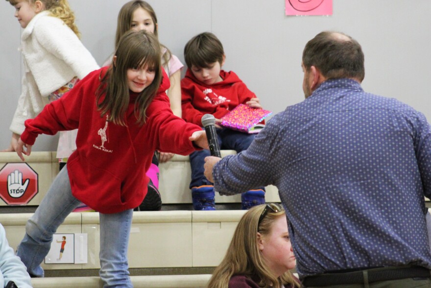 Kenai Peninsula Borough School District Superintendent Clayton Holland hands a microphone to Makayla Jicha during a public meeting to address the proposed closure of Sterling Elementary School due to budget cuts on Wednesday, Mar. 25, 2026 in Sterling, Alaska.