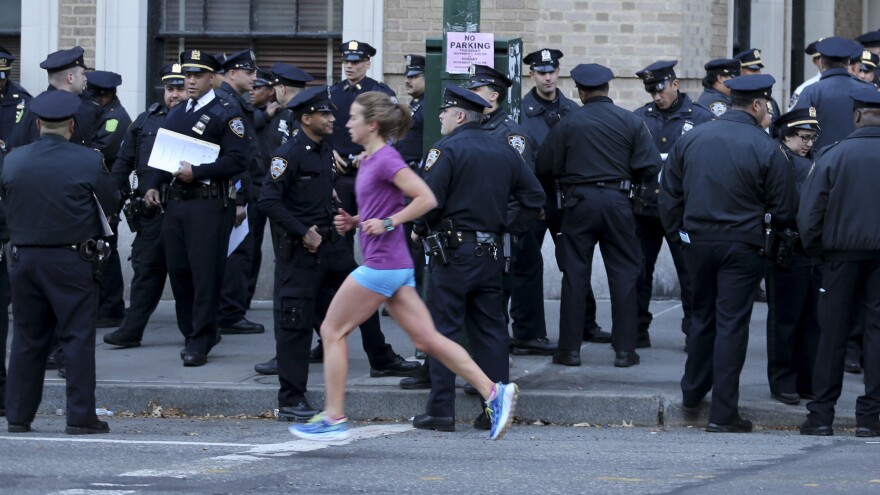A runner moves past a group of police officers gathered near the finish line of the New York City Marathon on Nov. 6, 2016. Authorities are increasing the number of officers and other law enforcement personnel for this year's race, in the wake of an Tuesday's terrorist attack in the city, in which a truck struck and killed eight bicyclists.