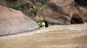 A member of a search and rescue team wades in to Virgin River during a search Wednesday, Sept. 16, 2015, in Zion National Park, near Springdale, Utah. Seven hikers who entered a narrow desert canyon for a day of canyoneering became trapped when a flash flood filled the chasm with water, killing at least five of them in Zion National Park in southern Utah, officials said Wednesday.