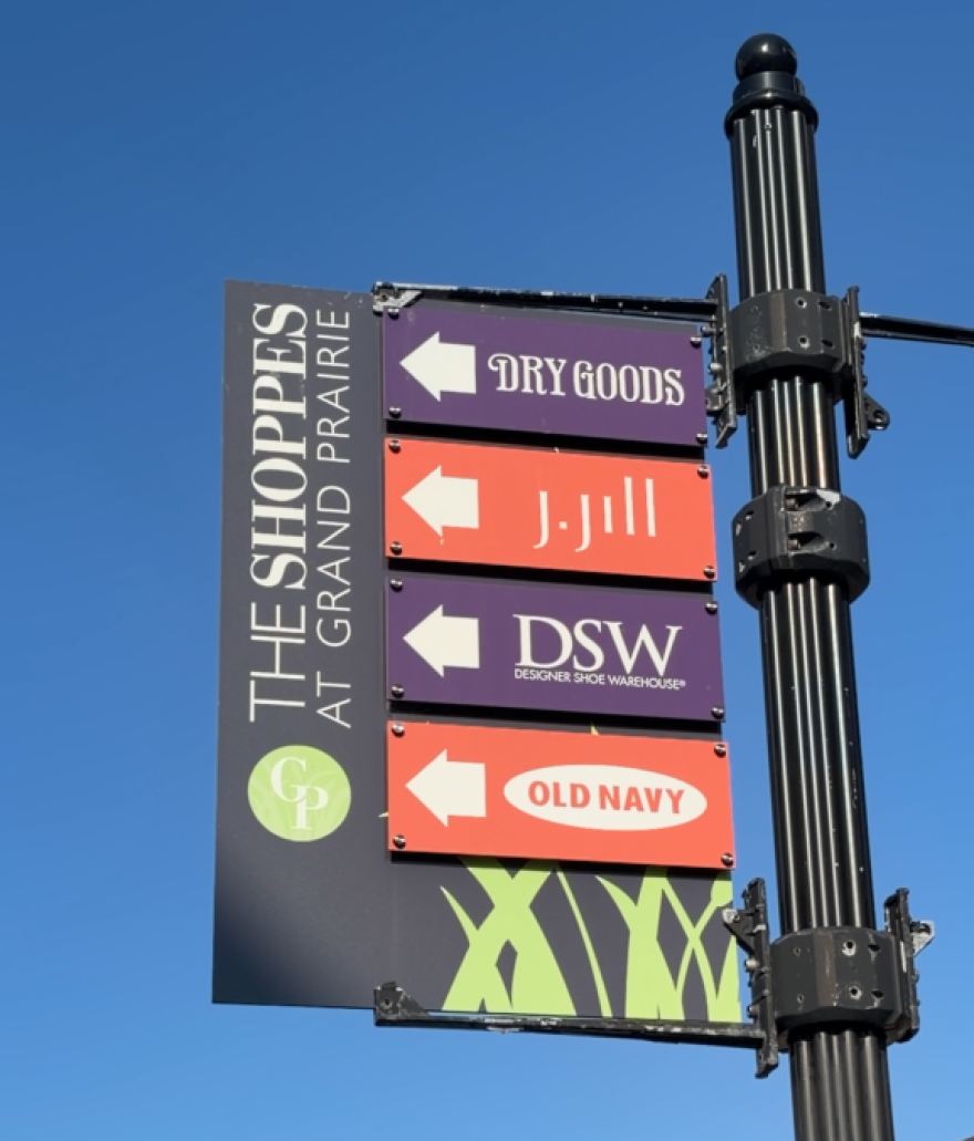 a wayfinding sign points to different stores in an outdoor mall
