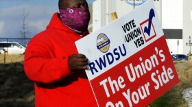 Michael Foster of the Retail, Wholesale and Department Store Union holds a sign outside an Amazon facility where labor is trying to organize workers on Tuesday, Feb. 9, 2021. (AP Photo/Jay Reeves, file)