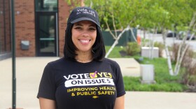 A woman smiles as she wears a matching hat and t-shirt, both reading "Vote yes on Issue 5," the t-shirt also reads, "improving health and public safety." 