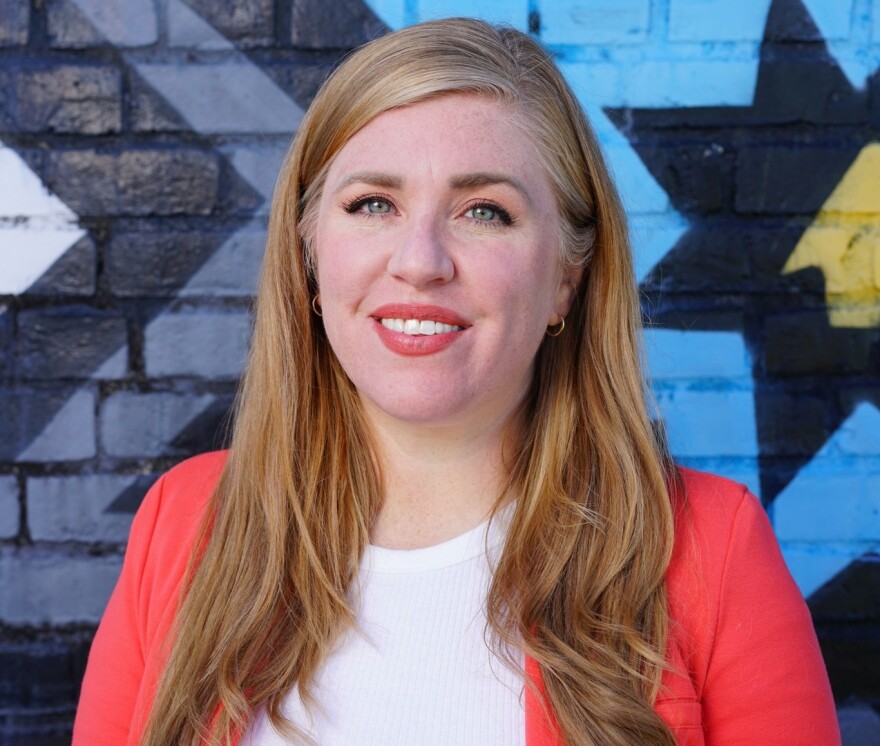 District 15 Metro Council Member Jennifer Chappell standing in front of a mural wearing a white t-shirt and coral cardigan.