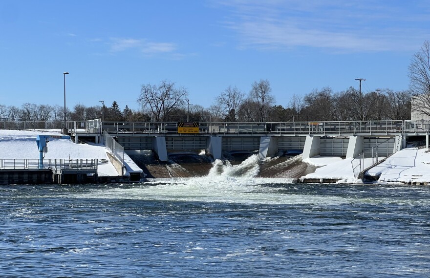 The Cheboygan River Dam's sea lamprey trap can hold up to a thousand lamprey. When sea lamprey are returning to the river to spawn in the spring, the trap needs to be emptied multiple times a day. The blue crane [on the far left] by the dam is used to lift the trap out of the water.