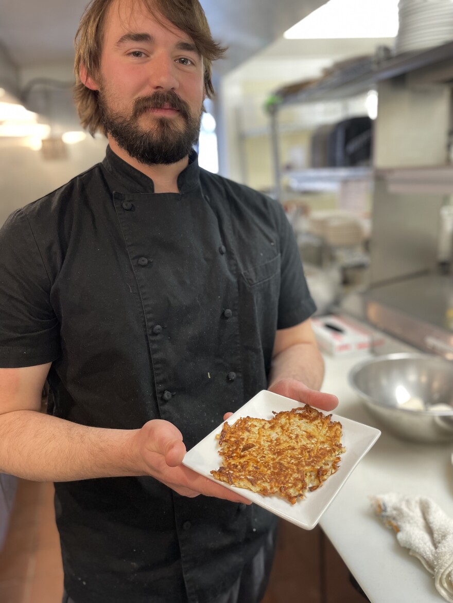 Chef Tyler Hadfield of the Rail in Orleans holding a plate of turnip latkes.