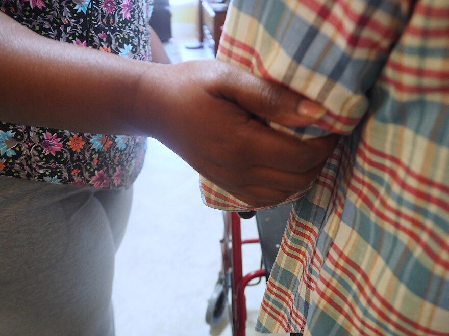 caretaker's hand on the arm of elderly patient