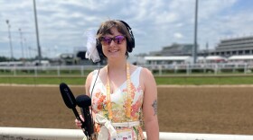 A reporter holds recording equipment trackside at Churchill Downs.