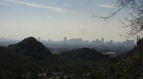 Brownish pollution hands in air over cityscape behind hills