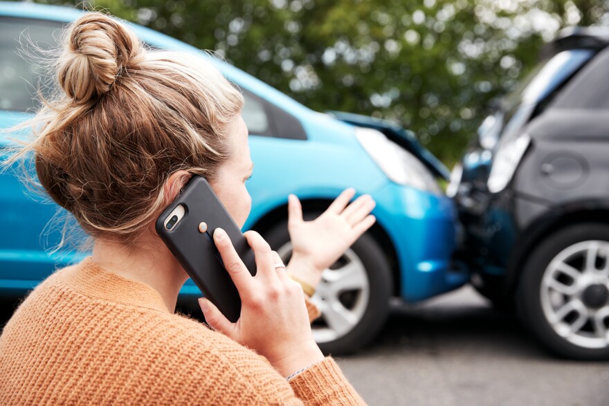 Female motorist involved in  car accident calling insurance company.