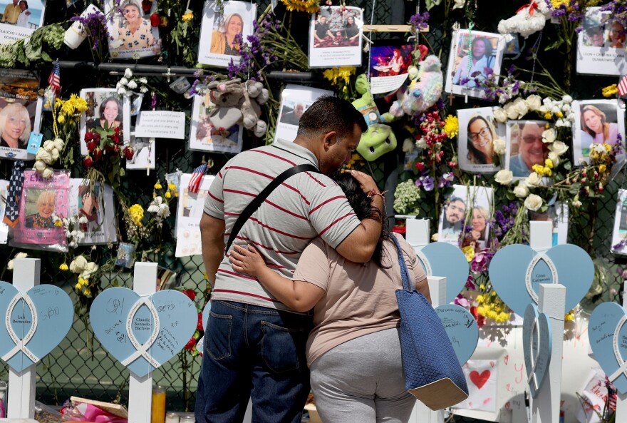 People hug at a memorial for victims of the collapsed Champlain Towers South condo building on July 8 in Surfside, Fla.