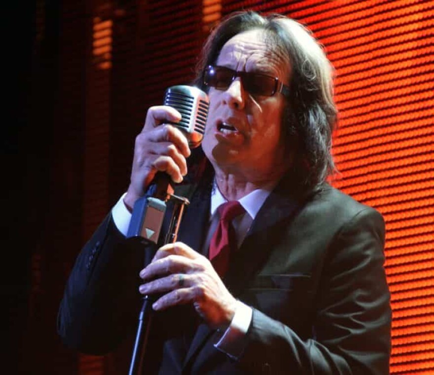 Old man with shoulder length hair sings into microphone