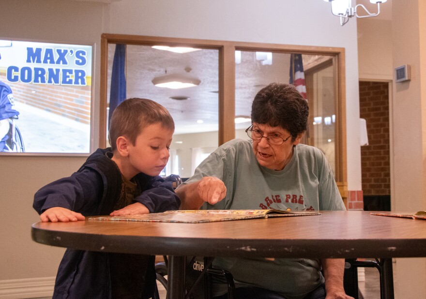 A pre-K student looks at a book with a “grandfriend” at Grace Skilled Nursing & Therapy in Norman.