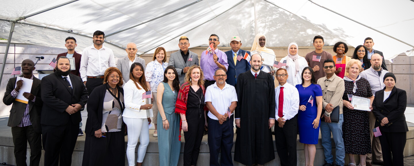 Newly-naturalized United States citizens pose for a photo just after their swearing-in ceremony at Centennial Plaza in the Cleveland Cultural Gardens on One World Day in August 2025.
