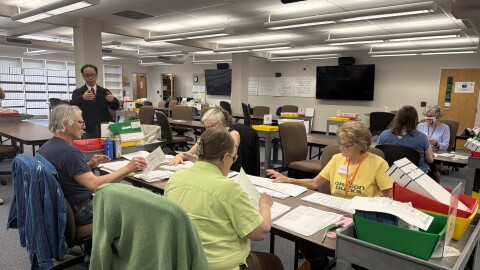 A group of Lane County Elections Office employees remove ballots from their envelopes and unfold them, preparing them to be scanned for vote counting, May 15, 2026.