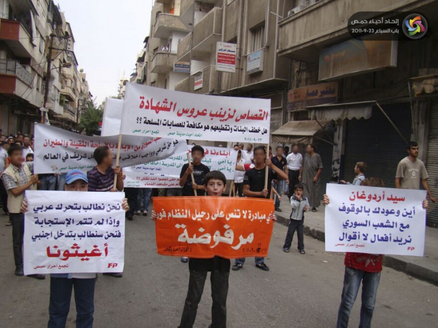 Syrian protesters hold up placards demanding intervention from other Arab countries during a demonstration against the Syrian regime in the central province of Homs on Sept. 23.