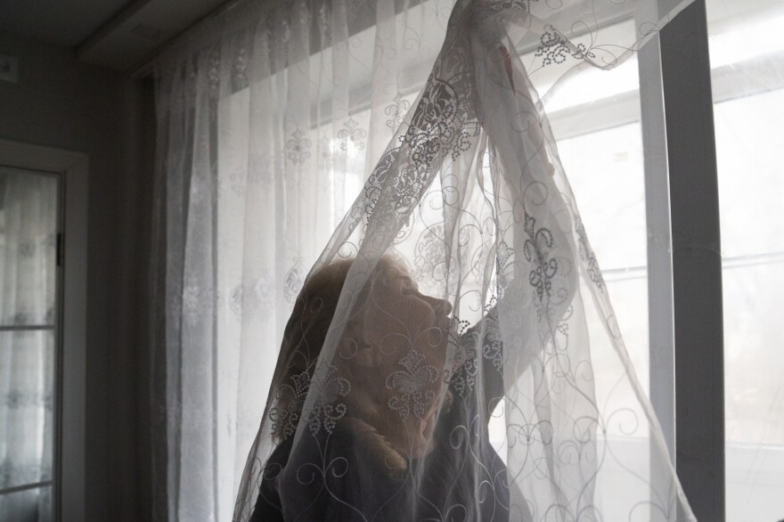 Liubov Lada arranges the curtains in the apartment she and her husband moved to after Russian shelling destroyed their old apartment.