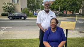 On a bench marking Waterbury’s Grand Street Cemetery, Wendy Tyson Wood, Treasurer of the Greater Waterbury NAACP, sits with her husband Dr. Kenneth Cook, Education Chair of the Greater Waterbury.